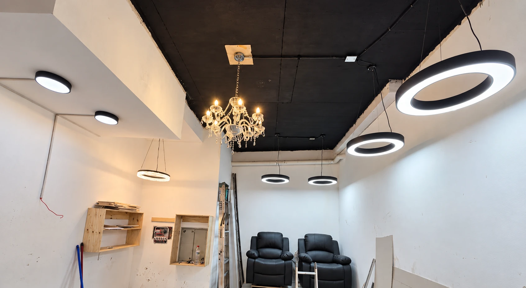 Aros LED suspendidos, plafones y una lámpara decorativa en un espacio en habilitación